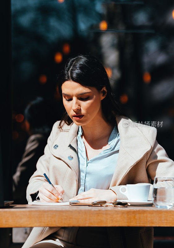 Portrait of a Beautiful Woman Writing in a Café on a Sunny Day